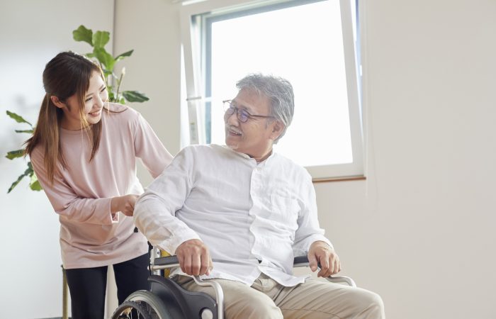 Young woman assisting senior man in wheelchair